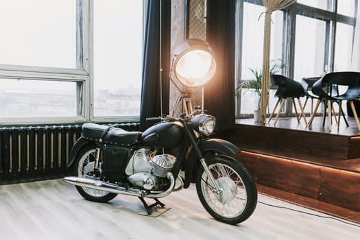 old retro motorcycle in a loft interior with a large lamp on the background