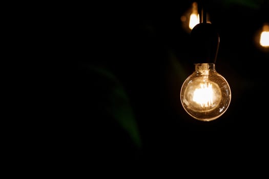 Classic Edison light bulb on black background with space for text