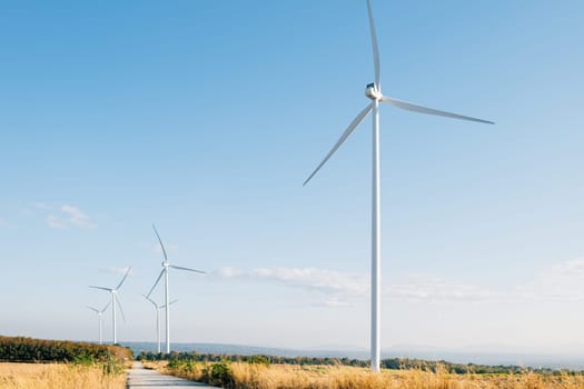 A mountain windmill farm signifies sustainable innovation with turbines harnessing clean wind energy. Modern technology shaping a green future against a vivid blue sky.