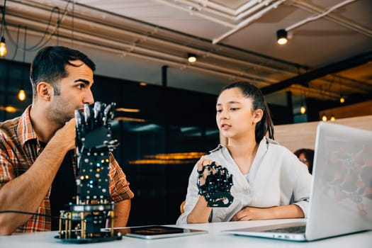 Teacher assists student constructing robotic arm in classroom for design and technology. Fostering innovation teamwork and discovery in science education. Robot hand. Innovation and technology concept