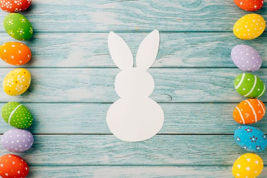 Easter Day Concept. Top view holiday banner background web design white colorful easter eggs and paper bunny rabbit on blue wood background with copy space, celebration greeting, overhead, template