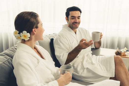 Beauty or body treatment spa salon vacation lifestyle concept with couple wearing bathrobe relaxing with drinks in luxurious hotel spa or resort room. Vacation and leisure relaxation. Quiescent