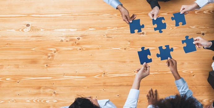 Panorama top view diverse corporate officer worker collaborate in office connect puzzle piece as partnership and teamwork concept. Unity and synergy in business success with jigsaw puzzle. Concord