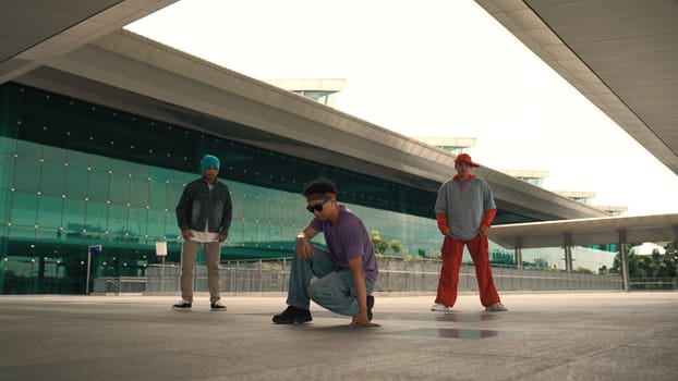 Group of diverse hipster or street dancer doing head spin in front of mall. Happy energetic break dancer practice b-boy step dancing with friends. Outdoor sport 2024. Street dancer concept. Sprightly.