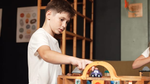 Multicultural girl playing toy to improve and develop creativity. Diverse student sitting while holding car model at playroom in elementary school at break time. Creative activity concept. Erudition.