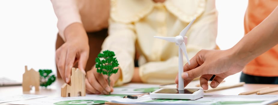 Windmill model represented using renewable energy placed during presenting green business on table with wooden block and environmental document scatter around. Closeup. Delineation.