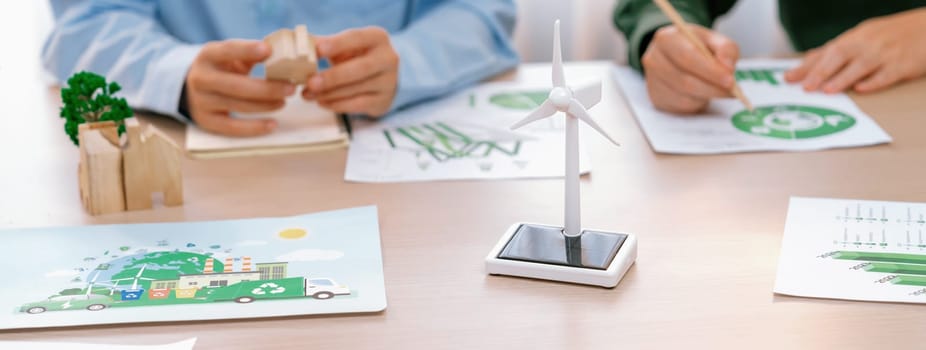 Business people invest in green business plan at meeting room on table with house model and wind mill placed represented eco house and renewable energy. Closeup. Delineation.