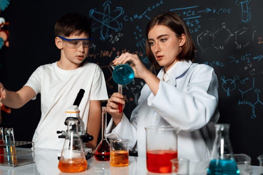 Teacher support schoolboy in laboratory. Schoolboy and teacher stand and experiment about science of chemistry in STEM class using liquid in glass container. Instructor mixing solution. Erudition.