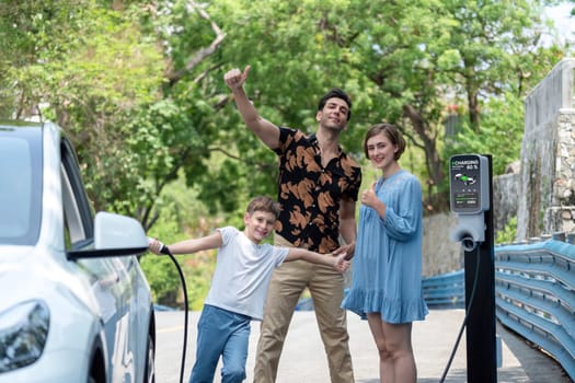 Family road trip vacation with electric vehicle, lovely family recharge EV car with green and clean energy. Natural and eco friendly car travel for sustainable environment. Perpetual