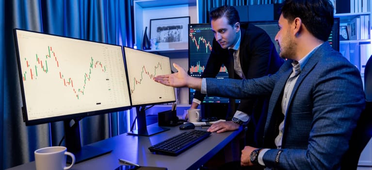 Stock exchange traders looking on high profit chart investment in panorama view, analyzing on monitor at night. Concept of discussing financial technology growth in neon light at workplace. Sellable.