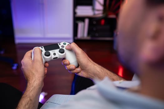 Focusing photo of holding joystick with fighting gaming competition of video game on blurred monitor screen. Controlling the button of joypad. Concept of lifestyles gamer in living room. Sellable.