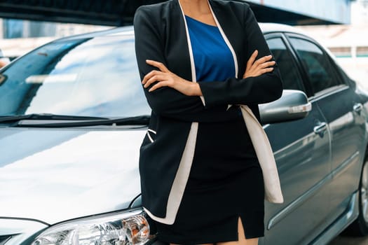 Confident professional business woman standing beside the car. Concept of car rental business and sales occupation. uds