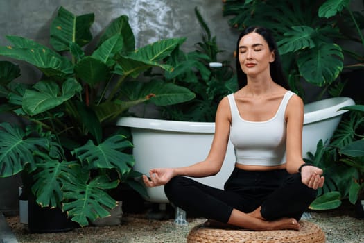 Young woman doing morning yoga and meditation in natural garden with plant leaf, enjoying the solitude and practicing meditative poses. Mindfulness activity and healthy mind lifestyle. Blithe