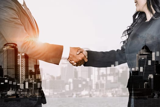 Double exposure image of business people handshake on city office building in background show partnership success of business deal. Concept of corporate teamwork, trust partner and work agreement. uds