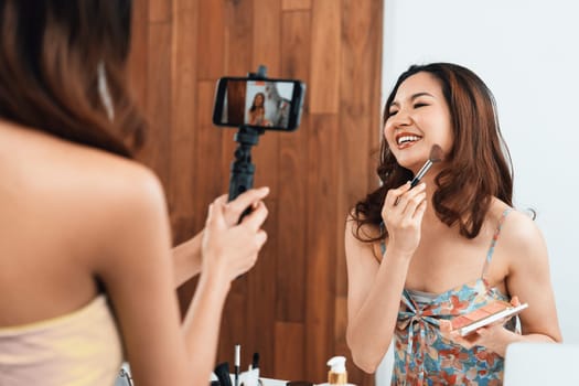 Asian Woman influencer shoot live streaming vlog video review makeup uttermost social media or blog. Happy young girl with cosmetics studio lighting for marketing recording session broadcasting online