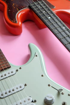 Electric guitar and bass guitar on a pink background with copy space.