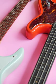 Electric guitar and bass guitar on a pink background with copy space.