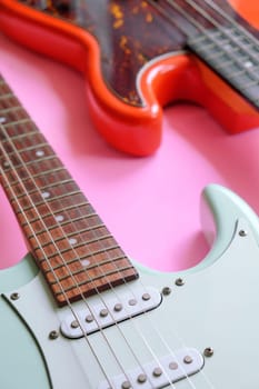 Electric guitar and bass guitar on a pink background with copy space.