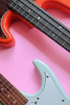 Electric guitar and bass guitar on a pink background with copy space.