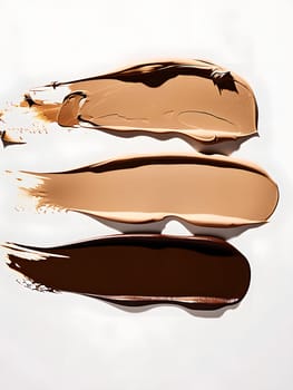 Three different shades of liquid foundation are stacked on top of each other, resembling a painting of peach tones. The gesture of blending ingredients creates a culinary art on a white surface