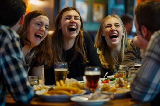 Female friends laughing while enjoying food and drinks with friends.