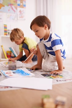 Boys, paper and painting on floor for creative development, fun activity and education in playroom. Children, bonding and drawing at home for learning, artistic hobby and homework together in house.