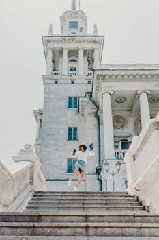 Woman staircase city. A business woman in a white shirt and denim skirt walks down the steps of an ancient building in the city.