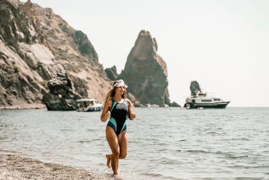 Woman beach vacation photo. A happy tourist in a blue bikini enjoying the scenic view of the sea and volcanic mountains while taking pictures to capture the memories of her travel adventure