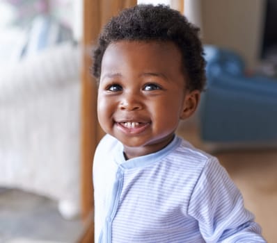Baby, smile or teeth in childcare, health or growth in play, leisure and relaxation in living room. Happy, black boy or child as curious, playful or fun in motor skill or childhood development.