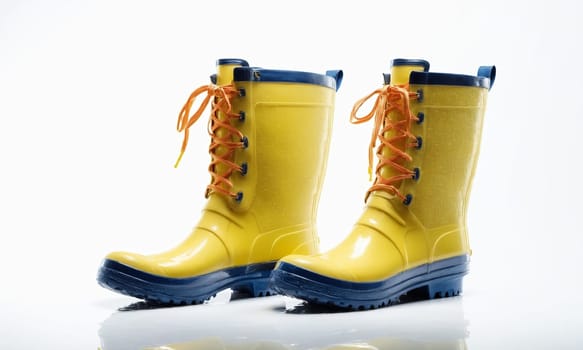 Pair of yellow rubber boots isolated on a white background with reflection.