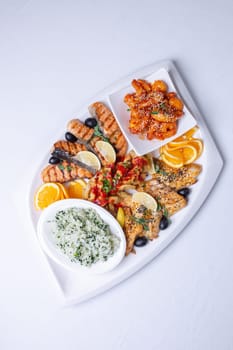 seafood mixture on a white grill. Delicious grilled fish, shrimp in sauce and salmon on the table.