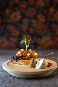 Rustic wooden plate with open faced sandwich with beef tenderloin and roasted mushrooms, garnished with fresh sprouts.