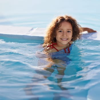 Child, girl and swimming with face, swimwear and blue summer sky for relax or smile. Kid, youth and sunshine with happiness, outdoor and play with curly hair and fun for sunny positivity or childhood.