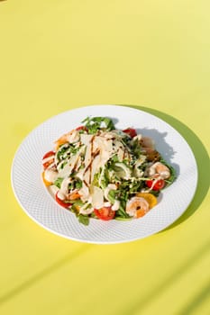 Delicious and healthy salad with greens, cherry tomatoes, and grilled shrimps. Served on a white plate, the image features a clean, modern look. Perfect for stock agencies or as a mockup.