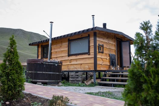 Wooden hot tub on the terrace of a house with a mountain landscape in the background. Relaxation and tranquility in nature.