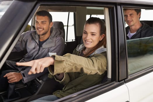 Friends, car and pointing on road trip with travel for adventure, vacation and sightseeing with happiness in countryside. Woman, men and driving in vehicle for holiday journey, tourism and scenery.