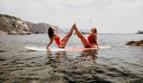 Woman sup yoga. Middle age sporty woman practising yoga pilates on paddle sup surfboard. Female stretching doing workout on sea water. Modern individual hipster outdoor summer sport activity