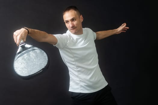 Paddle tennis player ready for serve on gray background. High quality photo