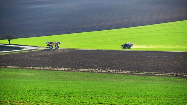 Tractor on the field in spring time. Green field in spring and tillage work. Concept for agriculture.