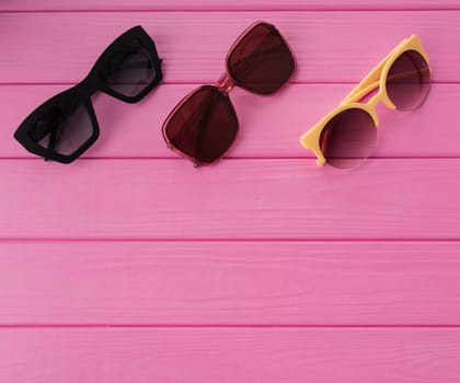 Summer abstract background mockup template free copy space for text pattern sample top view above on pink wooden board. blank empty area for inscription. Couple Stylish black sunglasses fashionable