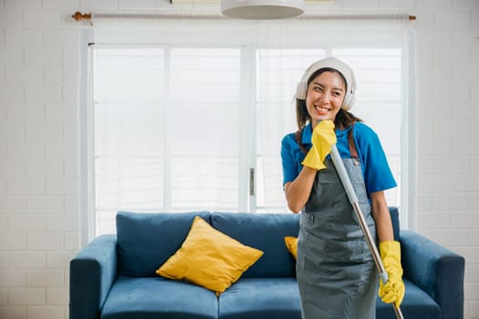 Happy young housewife enjoys singing her favorite song with mop as microphone during cleanup adding fun to housework. Dancing and cleaning in living room cheerful maid singing and playing with mop.