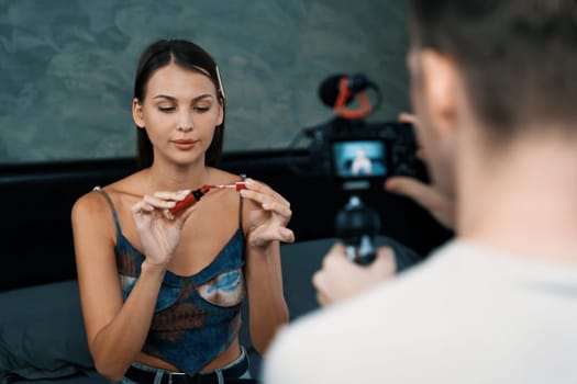 Man filming video on young woman making beauty and cosmetic tutorial video content for social media. Beauty blogger smiles to camera while showing how to beauty care to audience or follower. Unveiling