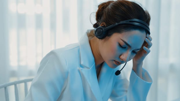 Businesswoman wearing headset working in office to support remote customer or colleague. Frustrated and tired call center customer support agent facing problem on providing vivancy service
