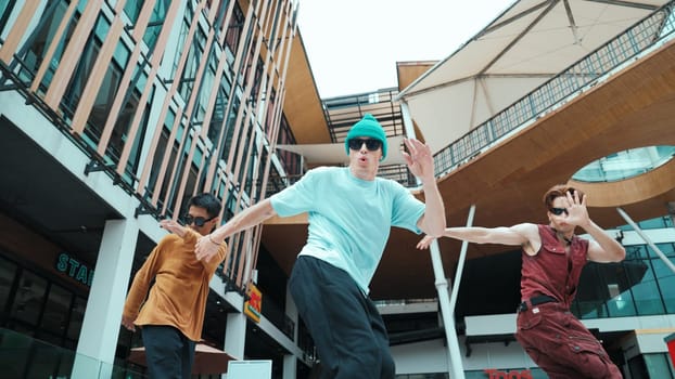 Caucasian group practice break dancing together. Energetic street dancer team in stylish fashion outfit perform hip-hop footstep at mall or city. Low angle view. Outdoor sport 2024. Endeavor.