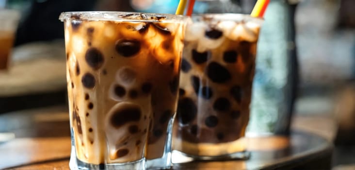 Milk Being Poured Into Iced Coffee on a dark table. Generative AI