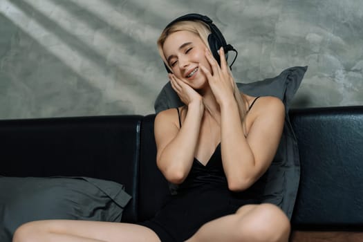 Young woman listening to music on headphone and enjoying meditative isolation on her bed with songs and, promoting a healthy lifestyle and relaxation with musical meditation. Blithe