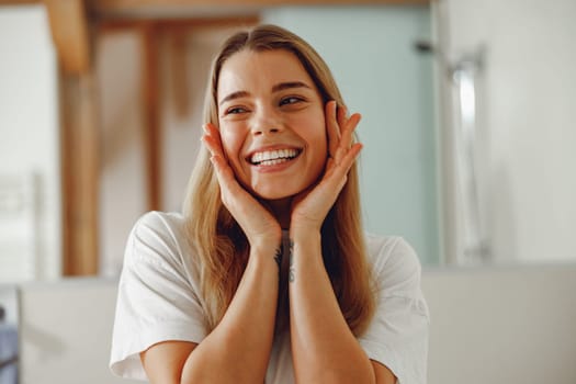 Attractive woman touching her pretty face and smiling while standing in bathroom