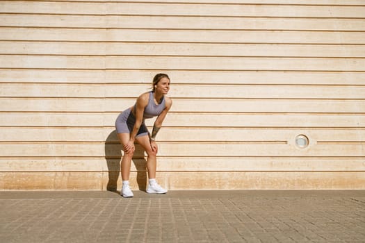 Female athlete in sportswear have a rest after morning jogging outside and looks away