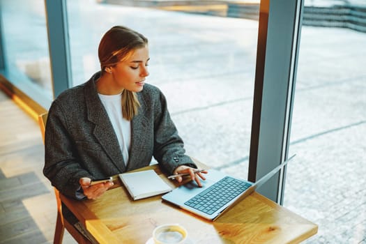 Smiling woman manager is using phone and work on laptop outside of office. Distance work concept