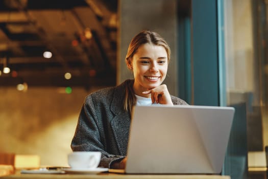 Stylish woman manager freelancer working on laptop while sitting in cozy cafe. High quality photo